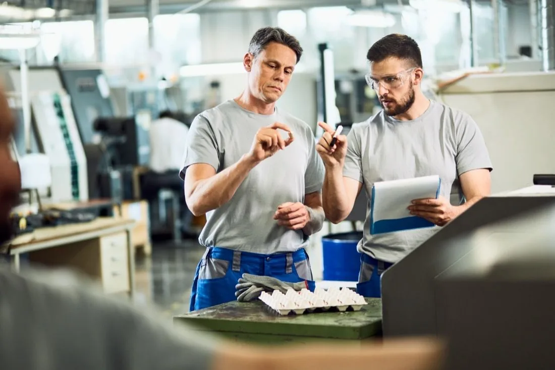 Zwei Mitarbeiter prüfen ein Werkstück an einer Maschine
