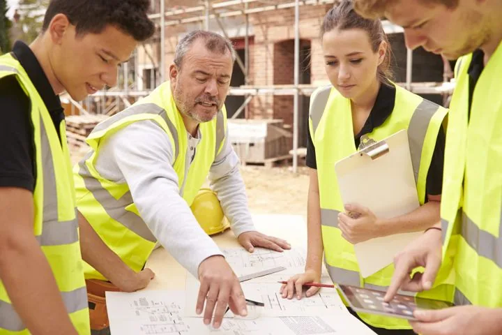 Bauleiter und Fachkraft für Arbeitssicherheit besprechen Pläne auf der Baustelle
