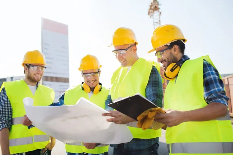 Bauarbeiter mit Helmen und Plänen auf einer Baustelle