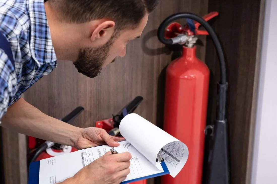 Prüfer mit Klemmbrett kontrolliert einen Feuerlöscher