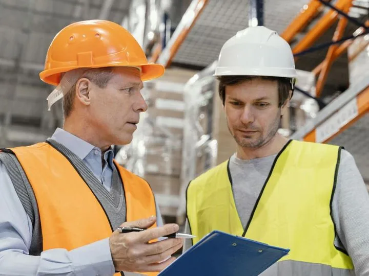 Fachkraft für Arbeitssicherheit bespricht eine Begehung mit einem Beschäftigten im Lager
