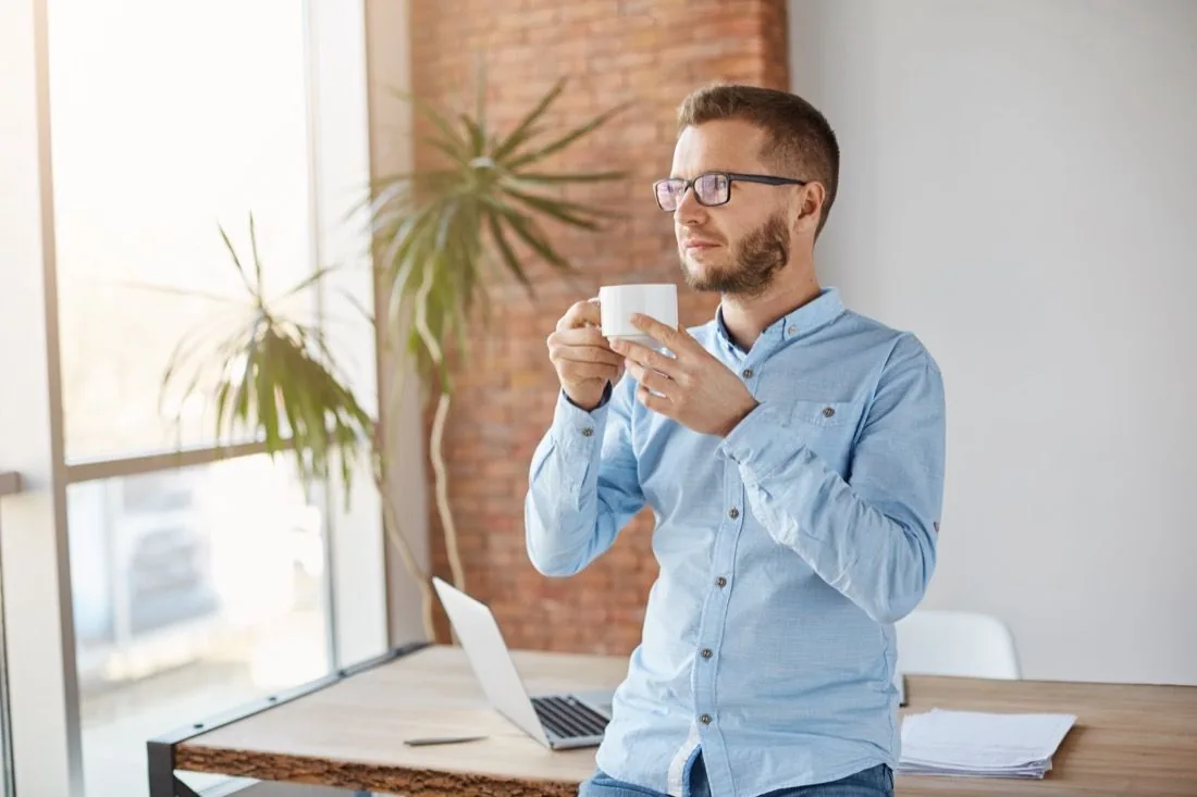 Mitarbeiter macht am Arbeitsplatz eine Pause mit einer Tasse